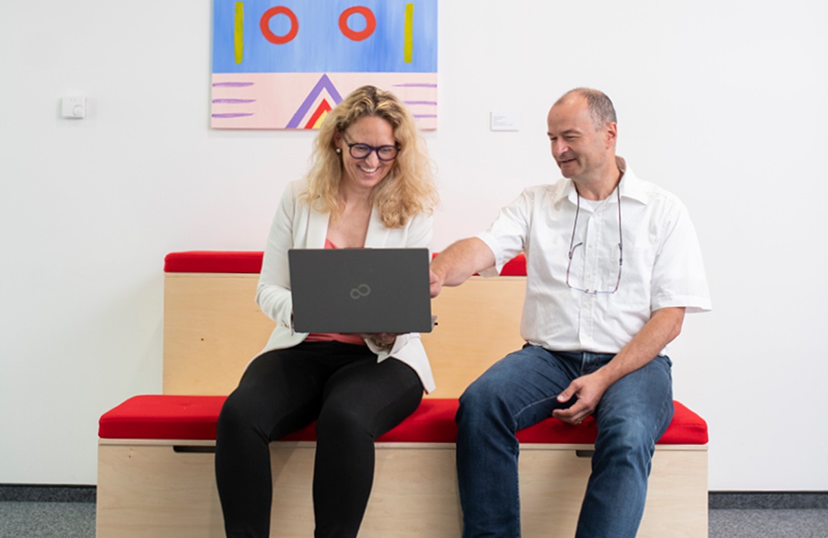 Zwei Personen im Gespräch mit Laptop