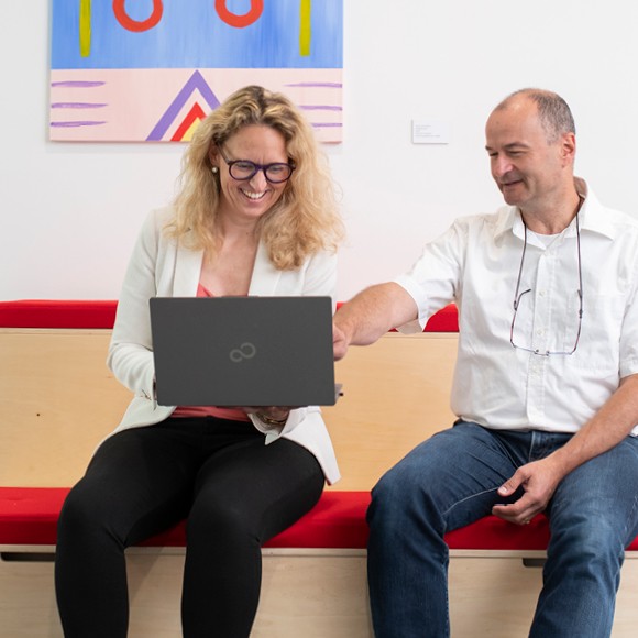 Zwei Personen im Gespräch mit Laptop